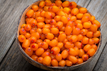 Buckthorn berry basket on wooden background.