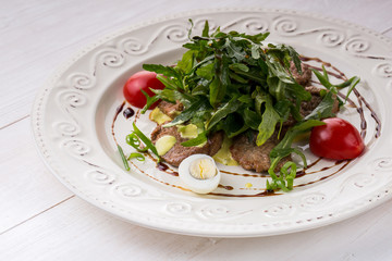 Salad with veal slices, arugula, tomatoes and eggs. over rustic
