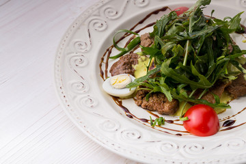 Salad with veal slices, arugula, tomatoes and eggs. over rustic