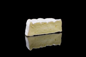ein stück camembert käse auf schwarzen hintergrund