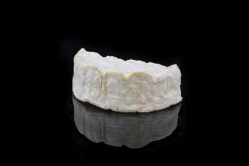 ein stück camembert käse auf schwarzen hintergrund