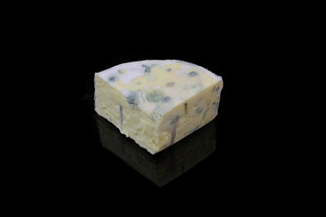 ein stück blauschimmelkäse auf schwarzen hintergrund