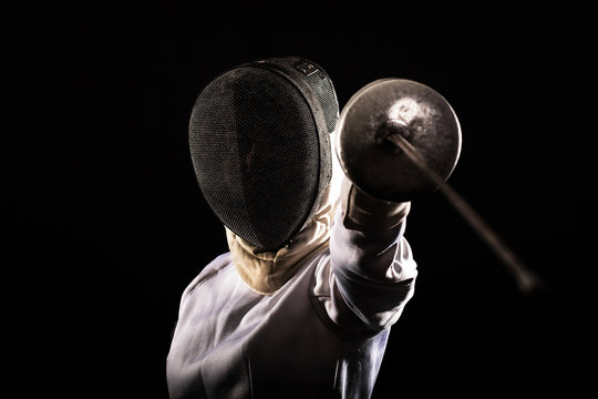 Portrait of woman wearing white fencing costume practicing with the sword.