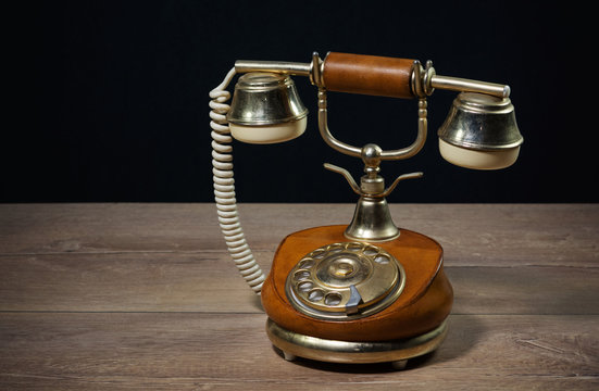 Elegant vintage phone on a wooden table with black background