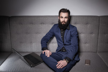 bearded man dressed in suit and with laptop browsing internet;