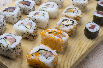 Different Sushi rolls,wasabi and ginger on a plate on wooden bac