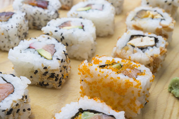 Different Sushi rolls,wasabi and ginger on a plate on wooden bac