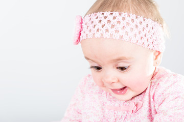 Portrait of 1 year old baby girl against grey background with copy space being amazed of her discovery