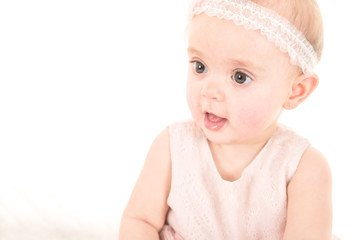 Close up shot of baby girl lookinn away from camera against white background