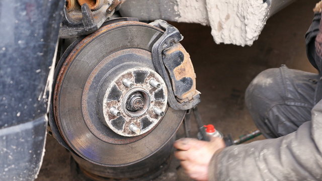 Auto mechanic working on brakes in a car repair shop domestic garage. 4K UHD video footage.