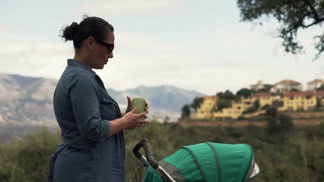 Young, pretty mother answer phone calls during walk with her son
