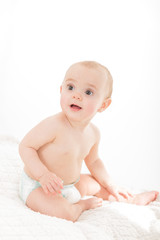 Baby with diaper looking away from camera on white background