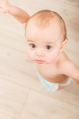 Above shot of less than 1 year old little girl being helped on her first steps in home interior