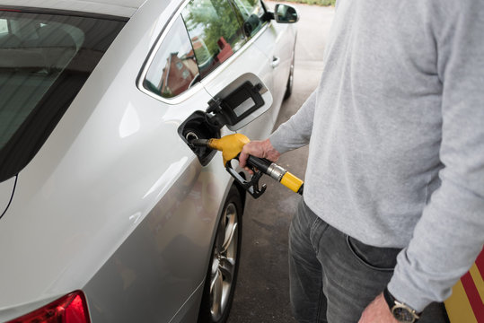 Man holding fuel pump nozzle and refilling car