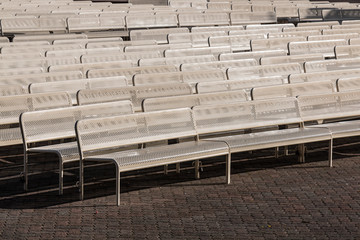 Empty audience benches in rows outdoors and facing right.