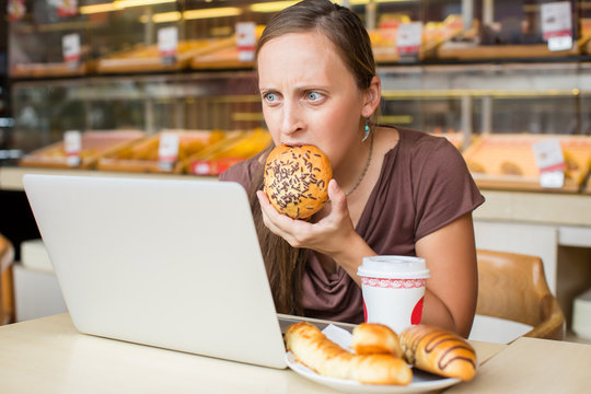 Pretty Young Woman Working At The Computer And Eat Bread. Unheal