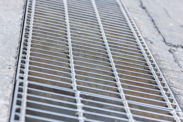 Black and white close up of a sidewalk subway grate with shallow