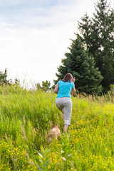 Woman and dog climb hill