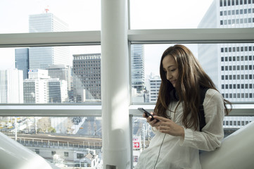 Fototapeta premium Beautiful woman looking at the smartphone in a modern building