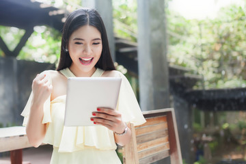 Cheerful happy Asian girl excited looking at touch pad tablet