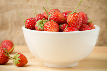 Fresh strawberry in the bowl on wooden background