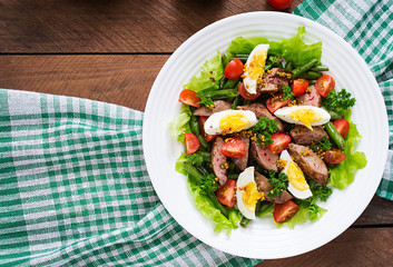 Warm salad with chicken liver, green beans, eggs, tomatoes and balsamic dressing. Top view