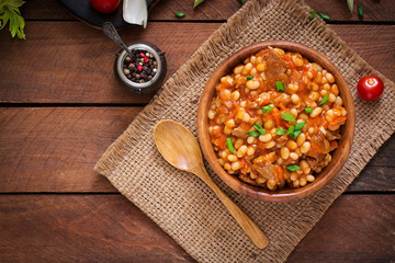 Steamed white beans with meat in tomato sauce. Top view