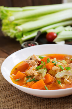 Tomato chicken soup with pumpkin, beans and celery in white bowl