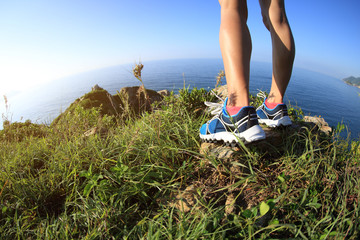 young fitness woman trail runner legs on seaside mountain peak