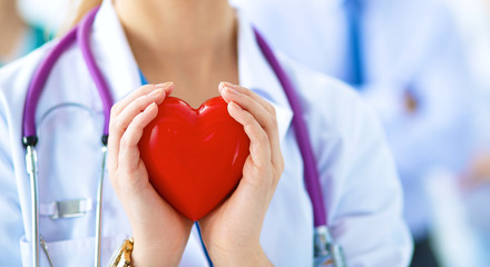 Female doctor with stethoscope holding heart