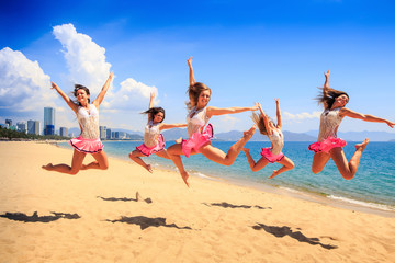 cheerleaders jump in Scales at once on beach against sea