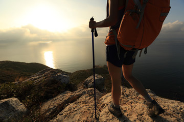 young woman backpacker at sunrise seaside mountain peak
