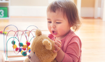 Happy toddler girl playing with her teddy bear