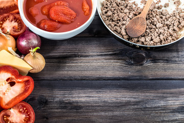 Ingredients of spaghetti bolognese arranged on wooden table.