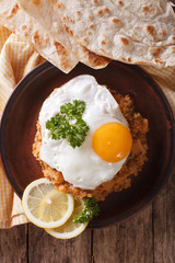 Egyptian breakfast: ful medames with a fried egg close-up. vertical top view
