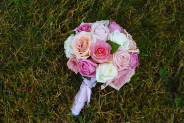 Wedding bouquet of yellow, pink and white roses  lying on green