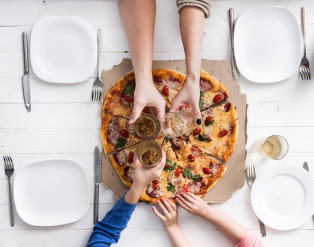 Family Clank Glasses Together Having A Dinner With Pizza