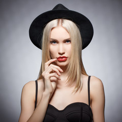 Luxury blonde young woman in a stylish black hat . Beauty portrait.