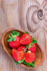 strawberries in a wooden bowl on the old wooden table