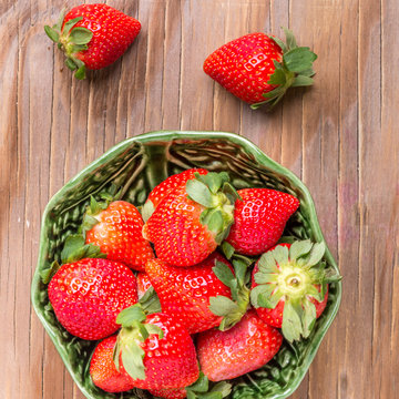 strawberries in a wooden bowl on the old wooden table