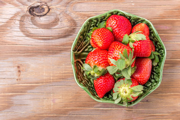 strawberries in a wooden bowl on the old wooden table