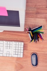 Color pencils in jar by computer at desk 