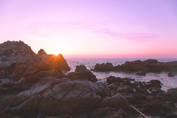 Rock on the beach with purple sunset