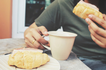 Woman drinking hot coffee with croissants