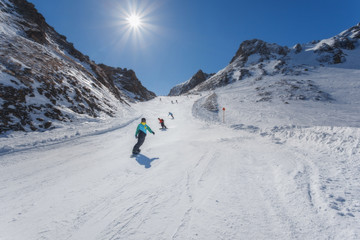 Fototapeta na wymiar Snowboarders and off the mountain on a sunny day. Austrian Alps.