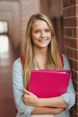 Smiling student with binder posing 