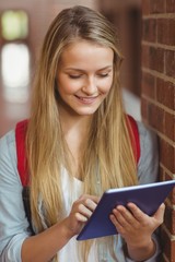 Smiling student using tablet in the hallway 