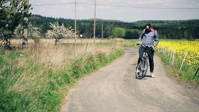Young man on bike taking photo on the country road
