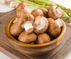 wooden bowl full of brown mushrooms