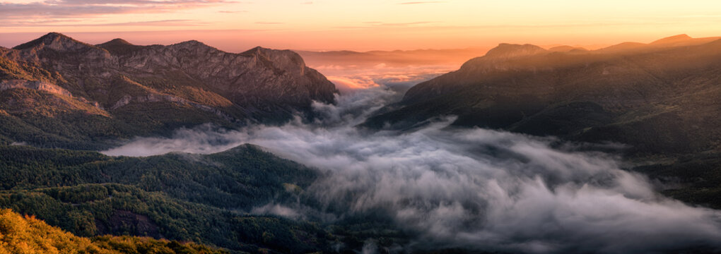 Fototapeta Rocky canyon with the  morning sun rays and clouds at the bottom